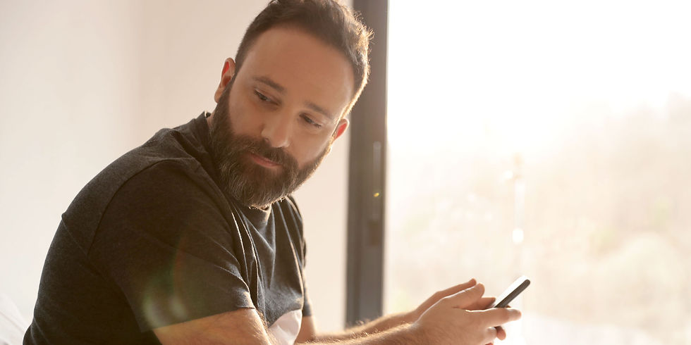 Mann mit Handy im Bett, Symbol für einfache erste Schritte ins passive Einkommen mit VestChance.